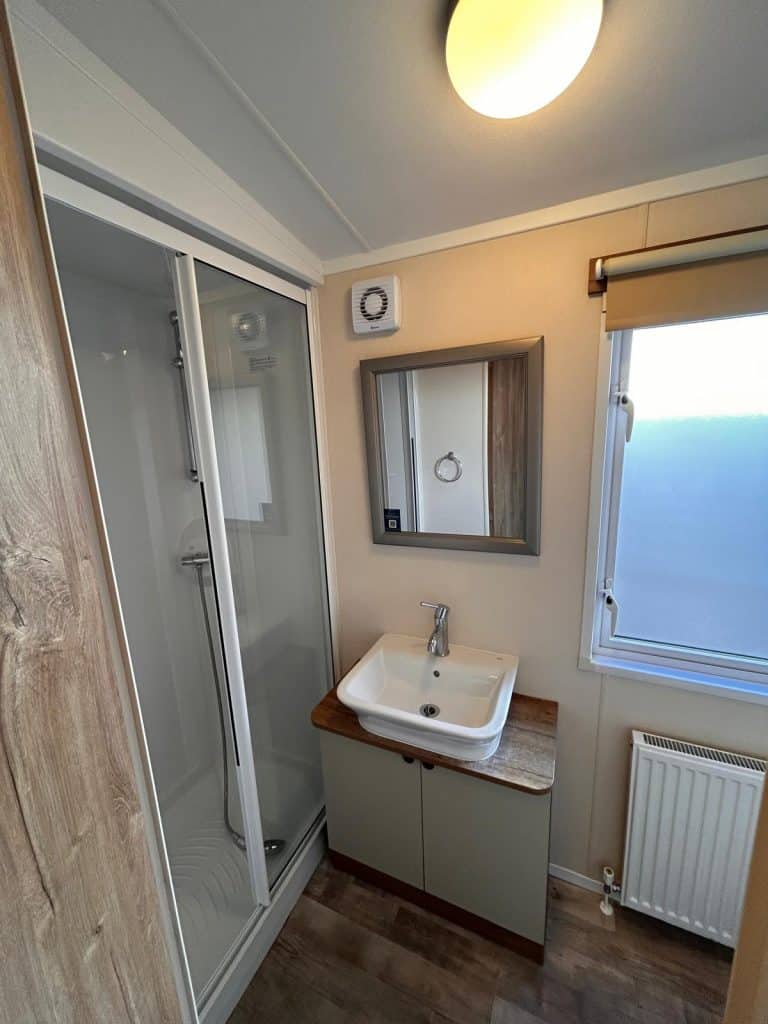 large shower cubicle with hand basin, mirror above