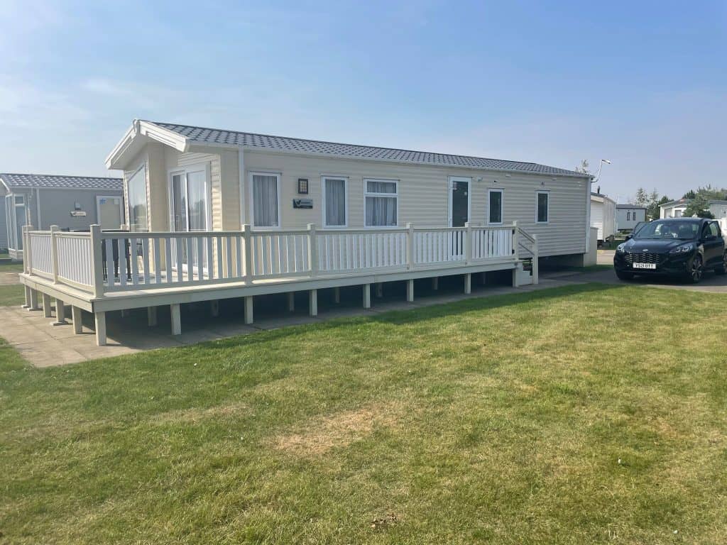 Cream static Caravan on a park with fencing around. Sell my Static caravan.