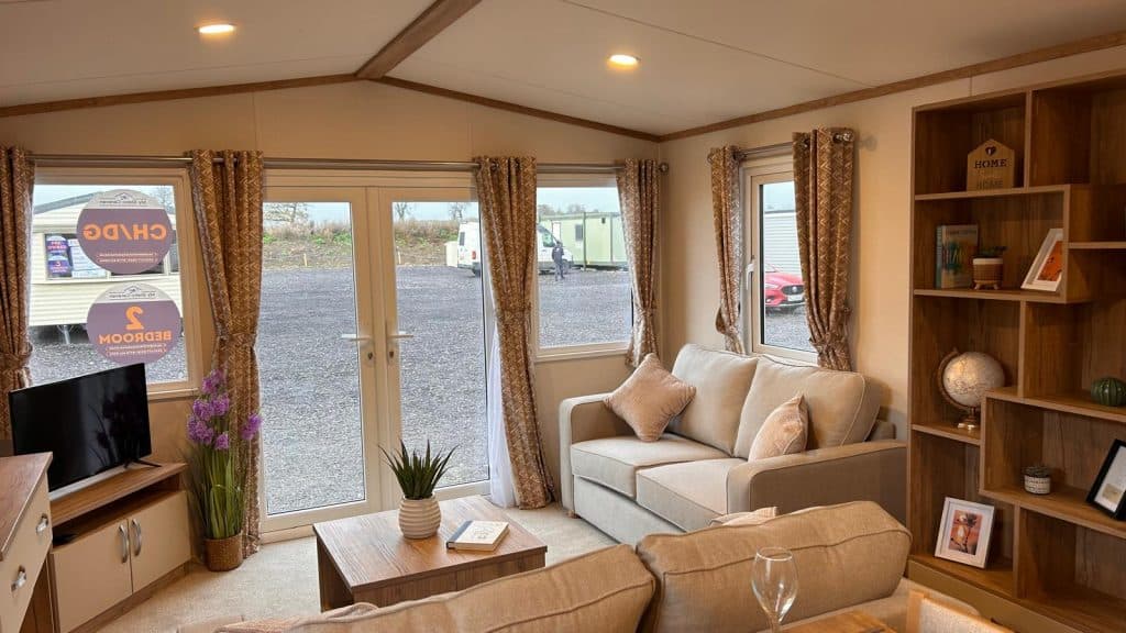 cream sofa with coffee table, bookcase, tv on tv cabinet. patio doors