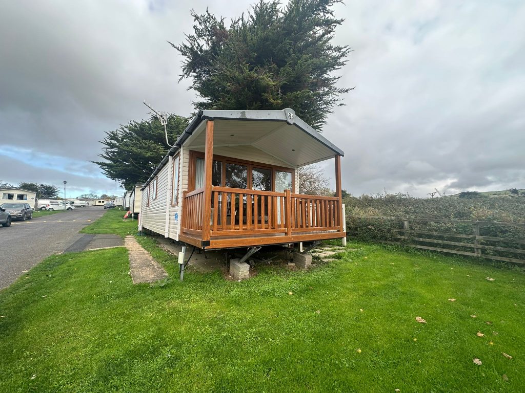 Static caravan with brown decking on grass pitch