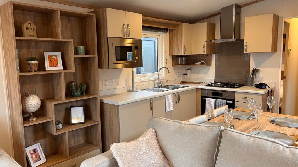 Cream kitchen cabinets with gas cooker and dining table with wine glasses