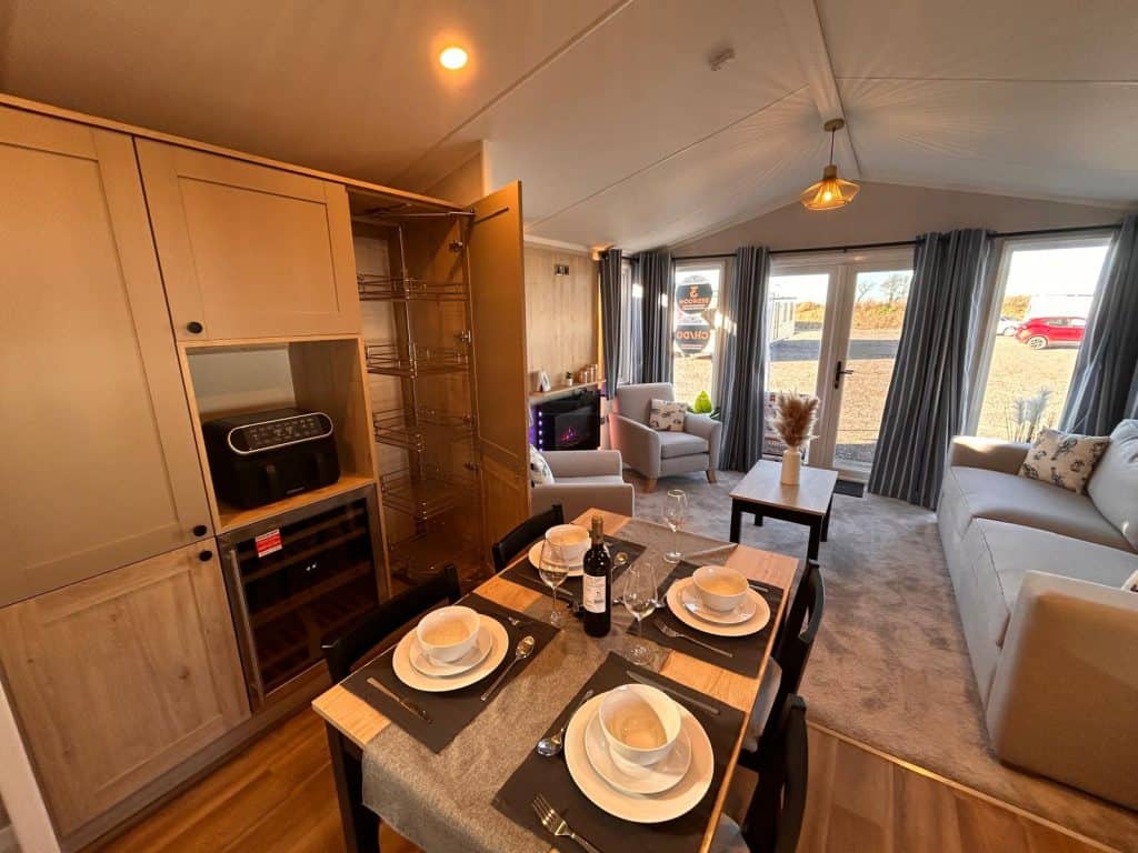 dining table with 4 place settings, wine bottle and larder cupboard.