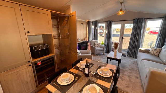 dining table with 4 place settings, wine bottle and larder cupboard.