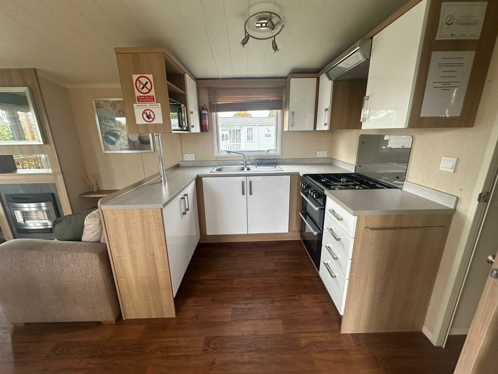 fitted kitchen with white units, gas cooker and window
