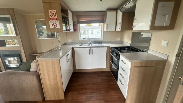 fitted kitchen with white units, gas cooker and window