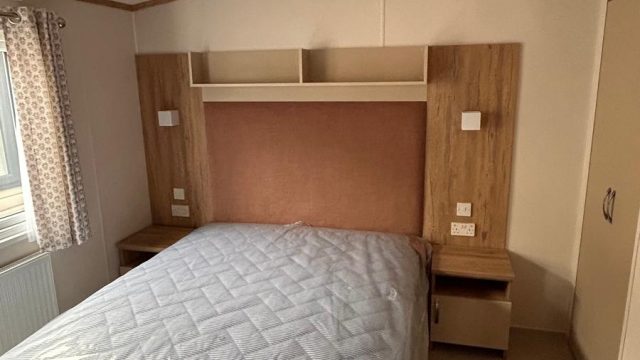 Double bed with shelving above bed and bedside tables