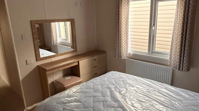 double bed and vanity table with mirror on wall