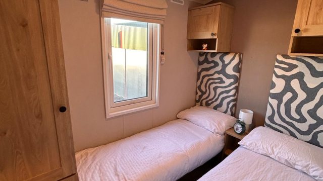 2 single beds with headboards and cupboard above bed