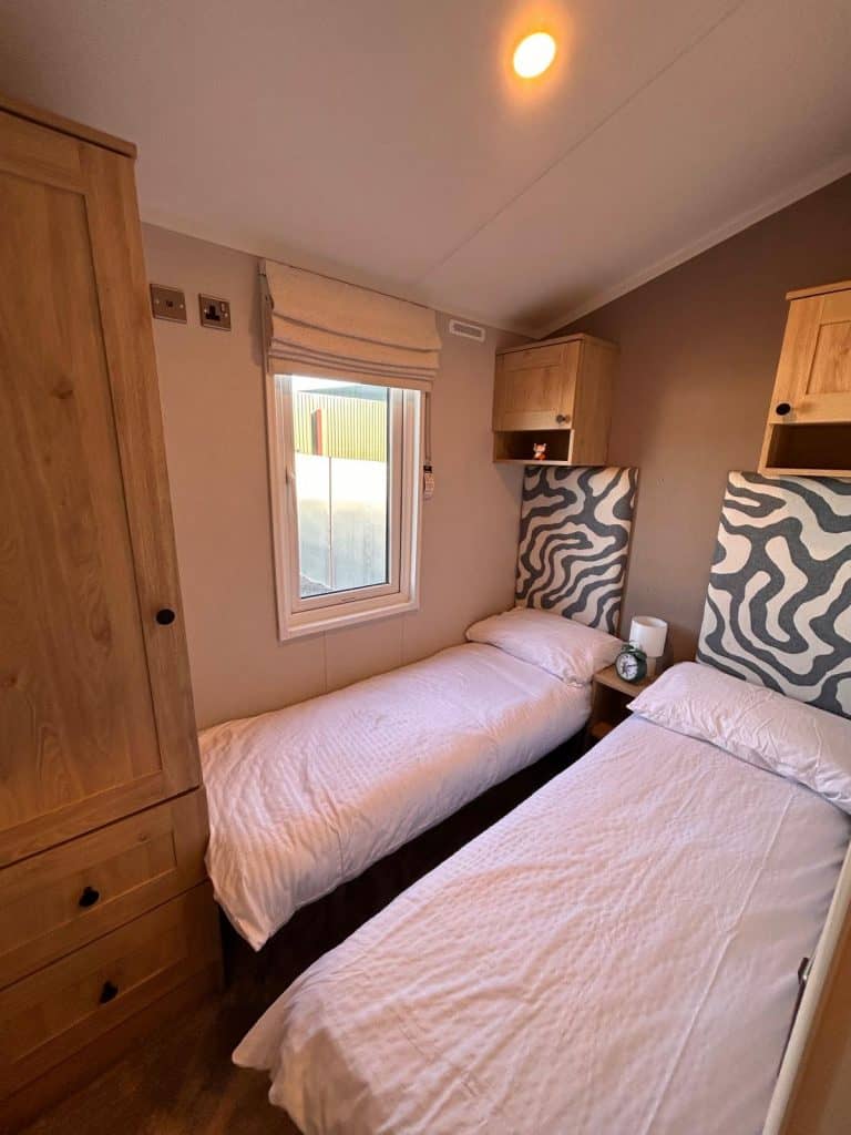 2 single beds with headboards and cupboard above bed