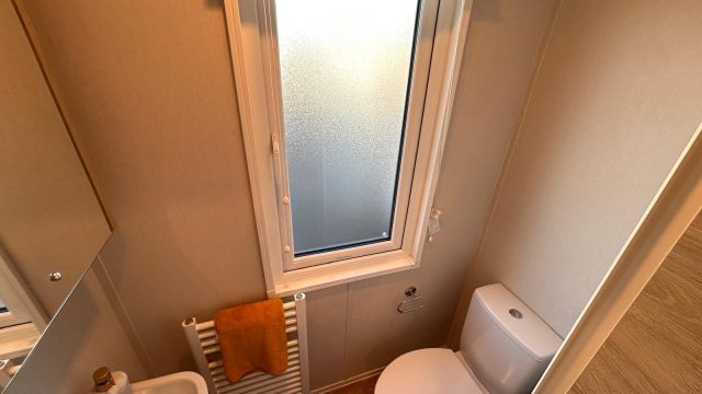 ensuite toilet with handbasin, yellow towel on towel radiator