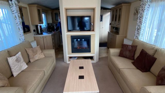 2 sofas with coffee table and electric fire and TV on wall