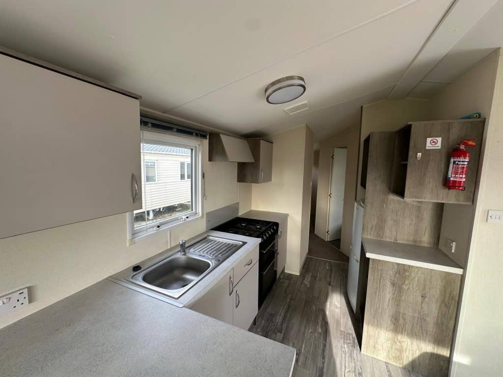 kitchen cupboards with sink by a window. Gas cooker and vinyl flooring