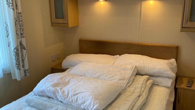 double bed with bedding. Over bed cupboards.