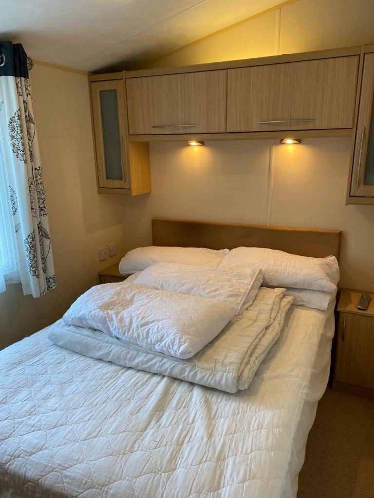 double bed with bedding. Over bed cupboards.