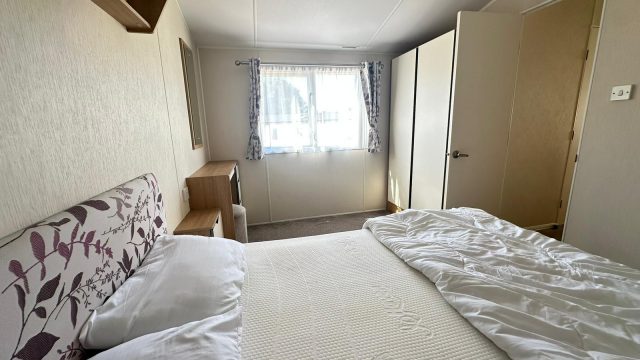 double bed with bedding, wardrobe in corner