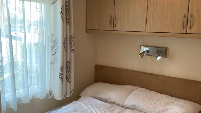 Double bed by window with over bed storage